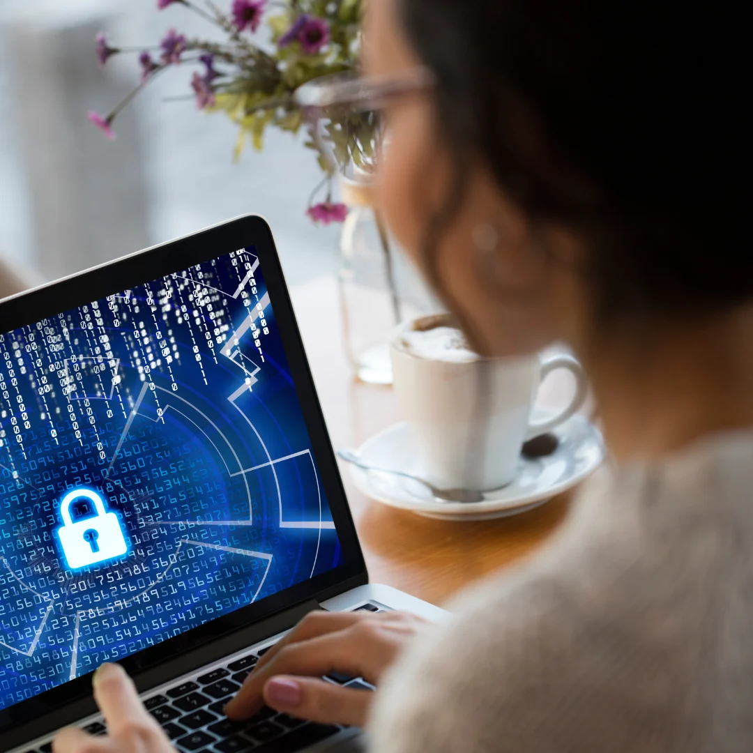Donna che lavora su un laptop con un'icona di sicurezza digitale sullo schermo, simbolo di protezione informatica.